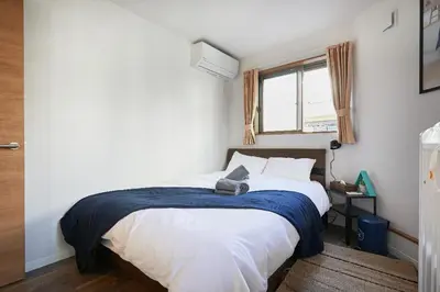 a bedroom with a bed with a blue blanket on it at Miraisya Hatsudai in Tokyo