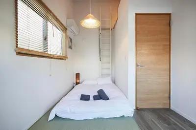 a bedroom with a white bed with two shoes on it at Miraisya Hatsudai in Tokyo