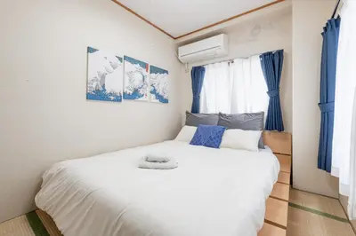 a bedroom with a white bed with blue accents at \u3071\u3093\u3060\u30db\u30b9\u30c6\u30eb\u5ca9\u8c37 in Tokyo