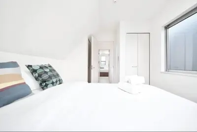 a white bedroom with a large bed and a window at miraisya shiinamachi in Tokyo