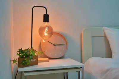a lamp on a table next to a clock on a bed at miraisya kyojima in Tokyo