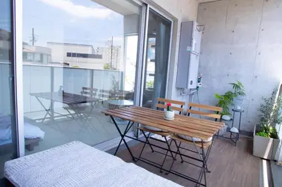 an apartment balcony with a wooden table and chairs at Monthly \u516d\u672c\u6728\u9ebb\u5e03\u30b9\u30ab\u30a4\u30c6\u30e9\u30b9 in Tokyo