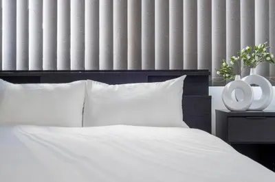 a bed with white sheets and two white vases on a table at Hanna Inn Shinbashi Onarimon in Tokyo