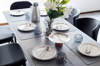 a table with white plates and a vase with flowers at Hanna Inn Shinbashi Onarimon in Tokyo