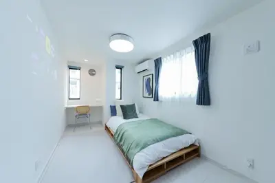 a white bedroom with a bed with a window at Seven's Inn Tateishi in Tokyo