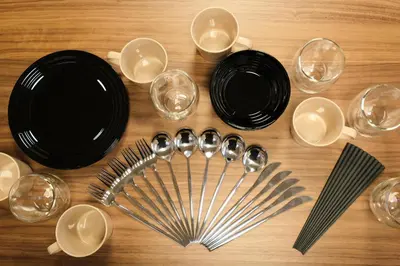 a table with black plates and wine glasses and spoons at MATSUBARA Inn by Tranova in Tokyo
