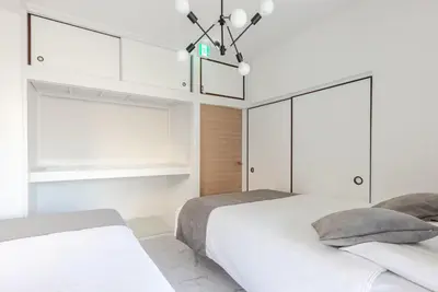 two beds in a bedroom with white cabinets and a chandelier at sgc\u6771\u7acb\u77f32\u4e01\u76ee in Tokyo
