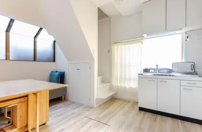 a kitchen with white cabinets and a wooden table at sgc\u6771\u7acb\u77f32\u4e01\u76ee in Tokyo