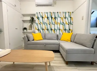 a living room with a gray couch and yellow pillows at sgc\u6771\u7acb\u77f32\u4e01\u76ee in Tokyo
