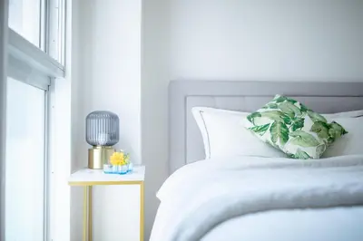 a white bedroom with a bed and a side table at 4 min to Shinjuku - Up to 8pax - 3BR - Near Shibuya, Harajuku in Tokyo