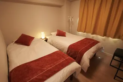 two beds in a hotel room with a window at SGC\u8535\u524d2\u4e01\u76ee3f in Tokyo