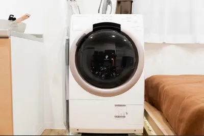 a washing machine in a room next to a bed at SAIE Sakura hotel in Tokyo