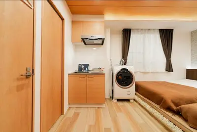 a room with a bed and a washing machine at SAIE Sakura hotel in Tokyo