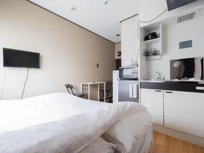 a white bedroom with a bed and a kitchen at Better Than Outside 12 min Shibuya by train in Tokyo