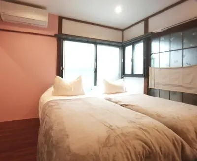 two beds in a room with two windows at \u53e4\u6c11\u5bb6\u9db4101\u5ba4 Tokyo\u65b0\u5bbf\u5730\u4e0b\u9244\u4e38\u306e\u5185\u7dda7\u5206 in Tokyo