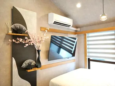 a bedroom with a bed and a vase with flowers at fukuhana \u6771\u65b0\u5bbf C3 in Tokyo