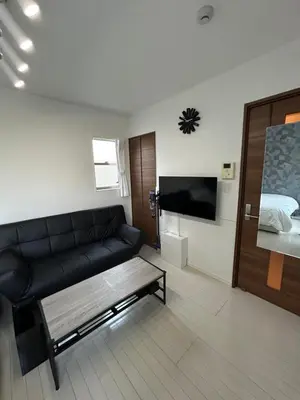 a living room with a black couch and a bed at Park side stay Shinjuku in Tokyo