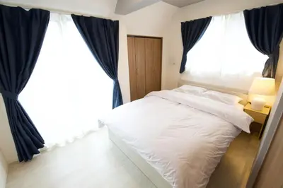 a bedroom with a white bed and blue curtains at Heureux\u690e\u540d\u753a 303 in Tokyo