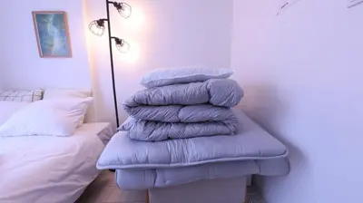 a stack of pillows sitting on a bench next to a bed at \u3089\u3057\u3063\u304f\u3059\u6c60\u888b204 in Tokyo