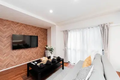 a living room with a couch and a tv on a wall at Shinjuku SAIEI Hotel 302 in Tokyo