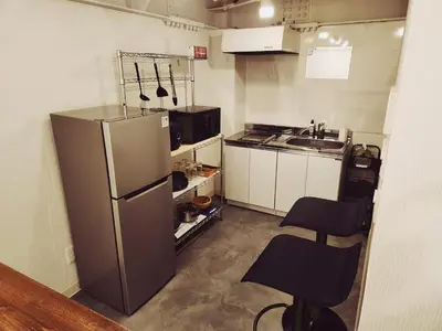 a small kitchen with a refrigerator and two chairs at The Hotel REPOS SUMIDA1 in Tokyo