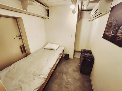 a small room with a bed and a suitcase at The Hotel REPOS SUMIDA1 in Tokyo