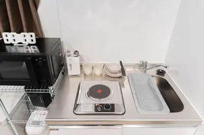a kitchen counter with a sink and a microwave at Shinjuku SAIEI Hotel 202 in Tokyo