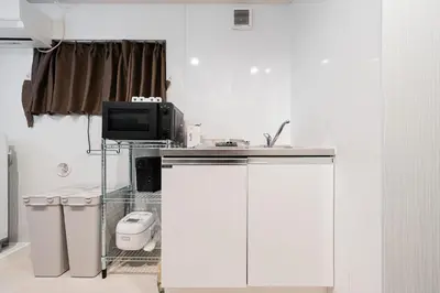 a kitchen with white cabinets and a tv in a room at Shinjuku SAIEI Hotel 202 in Tokyo