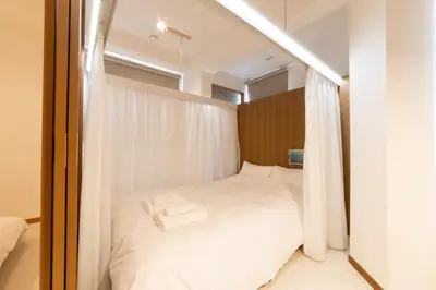 a bedroom with a bed with white sheets at Swan Lake Inn Shinjuku - Vacation STAY 19482 in Tokyo