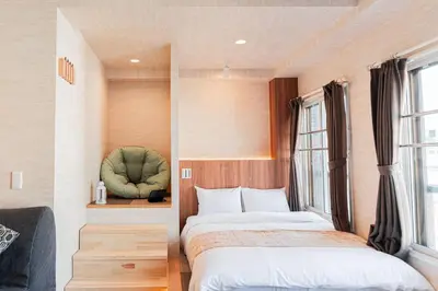 a bedroom with two beds and a green chair at Shinjuku SAIEI Hotel 501 in Tokyo