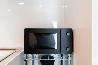a microwave oven hanging on a wall in a kitchen at Shinjuku SAIEI Hotel 502 in Tokyo
