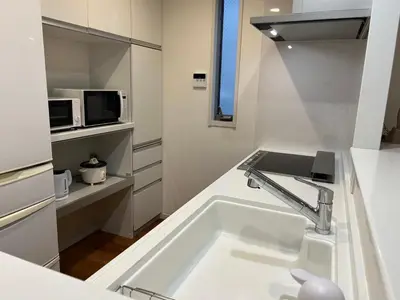 a white kitchen with a sink and a microwave at Yoyogi Premier 4BR House in Tokyo