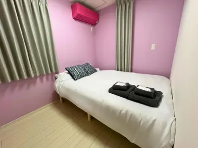 a small bed in a room with pink walls at Yoyogi Premier 4BR House in Tokyo