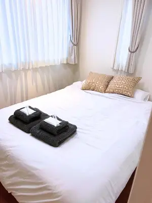 a white bed with two black towels on it at Yoyogi Premier 4BR House in Tokyo