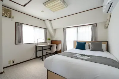 a bedroom with a bed and a desk and windows at \u767d\u7802\u30d3\u30eb in Tokyo