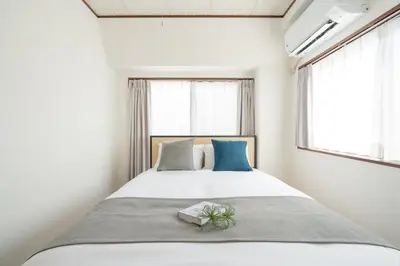 a bedroom with a large white bed with blue pillows at \u767d\u7802\u30d3\u30eb in Tokyo