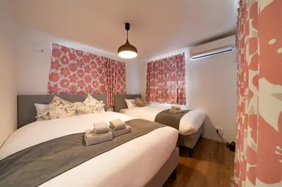 two beds in a small room with red curtains at \u845b\u98fe\u9ad8\u7802\u6238\u5efa in Tokyo