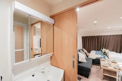 a bathroom with a mirror and a bed and a couch at Shinjuku SAIEI Hotel in Tokyo