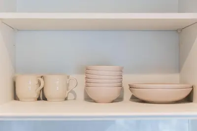 a shelf with cups and bowls on it at Shinjuku SAIEI Hotel in Tokyo