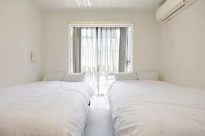 two beds in a white room with a window at \u767d\u91d16\u4e01\u76ee401 in Tokyo