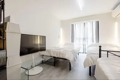 a white room with two beds and a flat screen tv at \u767d\u91d16\u4e01\u76ee401 in Tokyo