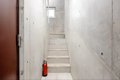 a fire hydrant sitting in a hallway with a staircase at \u767d\u91d16\u4e01\u76ee401 in Tokyo