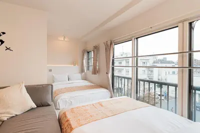 two beds in a room with a balcony at Shinjuku SAIEI Horizon Hotel in Tokyo