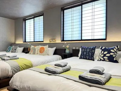 two beds in a room with three windows at nestay villa tokyo nippori in Tokyo