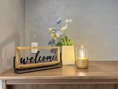 a welcome sign on a table with flowers and a candle at nestay villa tokyo nippori in Tokyo