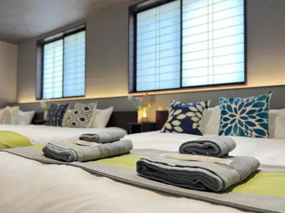 two beds with towels on them in a room with windows at nestay villa tokyo nippori in Tokyo