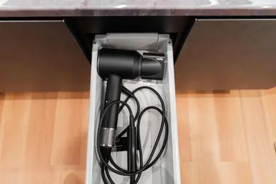 a black hair dryer in a box under a counter at Shinjuku SAIEI Hotel 201 in Tokyo