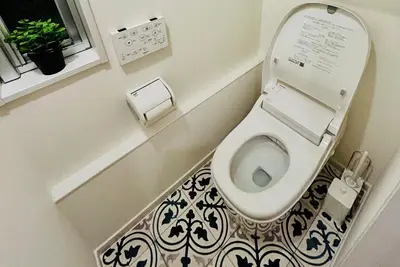 a bathroom with a toilet with a black and white tile floor at \u6674Hare Hotel in Tokyo
