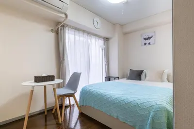 a bedroom with a bed and a table and a window at tokyo mirai 3F in Tokyo
