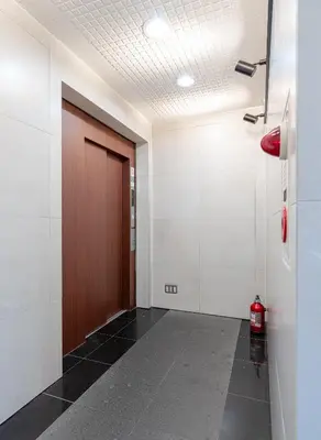 a hallway with a door and a fire extinguisher at tokyo mirai 3F in Tokyo